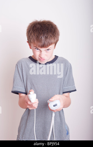 Ein MODEL Release Bild eines 10 Jahre alten Jungen spielen mit einer Nintendo Wii-Fernbedienung und Numchuck im studio Stockfoto