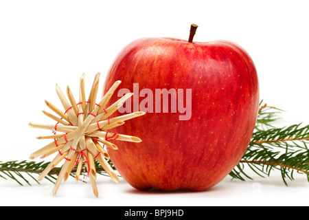 roter Apfel mit einem Stroh Stern vor einem Zweig auf weißem Hintergrund