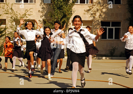 Aserbaidschan, Baku, Schülerinnen und Schüler in Uniformen laufen und springen während ihrer Pausenzeit Stockfoto