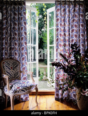 Bedruckten Stoff Vorhänge auf Französisch Türen zum Garten. Mit kostenlosen Stil Stuhl. Stockfoto