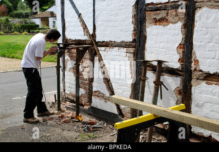 Renovierung einer alten Holz gerahmt denkmalgeschütztes Gebäude Arbeiter Ziegel entfernen & Rendern vor der Installation des neuen Eichenbalken Stockfoto