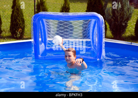 Teenager spielen Wasserball im Gartenpool. Stockfoto