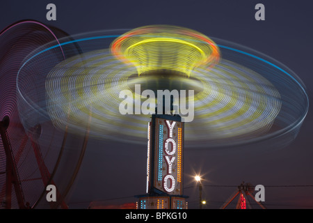 Die bunt beleuchteten Yo Yo dreht sich vor dem sanften Riesenrad am Nachthimmel an der New Jersey State Fair Stockfoto