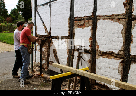 Renovierung einer alten Holz gerahmt denkmalgeschütztes Gebäude Arbeiter Ziegel vor dem Einbau des neuen Eichenbalken entfernen Stockfoto