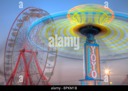 Die bunt beleuchteten sanfte Riesenrad und Yo Yo drehen gegen den Himmel in der Dämmerung während der New Jersey State Fair Stockfoto