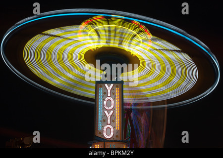 Die bunt beleuchteten Yo Yo dreht sich vor dem sanften Riesenrad am Nachthimmel an der New Jersey State Fair Stockfoto