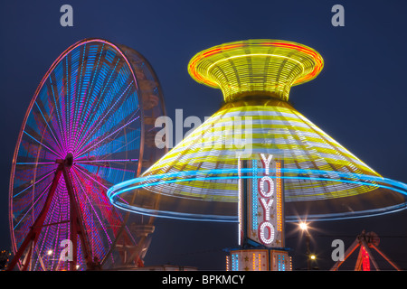 Die bunt beleuchteten Yo Yo dreht sich vor dem sanften Riesenrad am Nachthimmel an der New Jersey State Fair Stockfoto