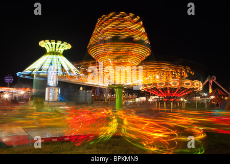 Bunt beleuchtete Fahrten mit dem Sizzler im Vordergrund, drehen gegen den Nachthimmel während der New Jersey State Fair Stockfoto