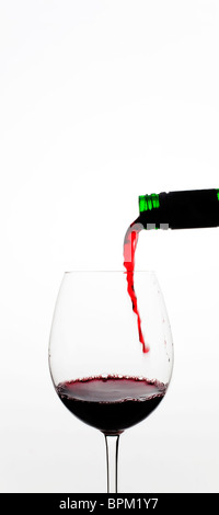 Rotwein gegossen in Glas vor weißem Hintergrund Stockfoto