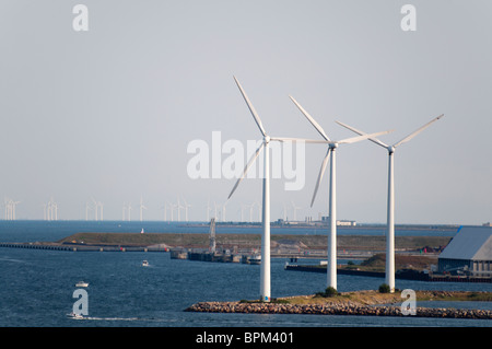 Drei Windkraftanlagen auf einer Insel in der Nähe von Copenhagen Hafen mit einem Windpark in der Ferne in Kopenhagen, Dänemark. Stockfoto