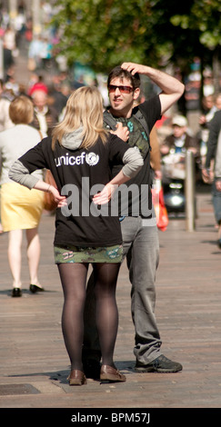 Ein weiblicher Liebe Arbeiter hält einen Mann in einer Glasgow-Straße um ihn für eine monatliche Spende Lastschriftverfahren anmelden. Stockfoto