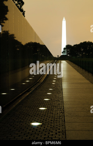 WASHINGTON DC, USA – die Mauer der Namen am Vietnam Veterans Memorial wird nachts beleuchtet, während das Washington Monument in der Ferne leuchtet. Die Gedenkstätte ehrt die Tausenden von Mitgliedern des amerikanischen Militärs, die im Vietnamkrieg ihr Leben verloren haben. Die reflektierende Mauer schafft eine feierliche und friedliche Nachtszene in der National Mall. Stockfoto