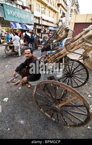 Eine Rikscha-Puller Ruhe durch seine Rikscha in den alten Straßen von Kalkutta. Stockfoto