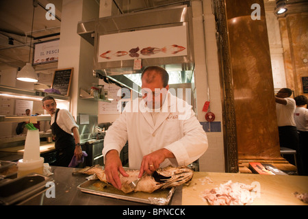 Ein Arbeiter bereitet, Striped Bass bei Eataly handwerklichen italienisches Essen und Weinmarkt in New York zu dienen Stockfoto