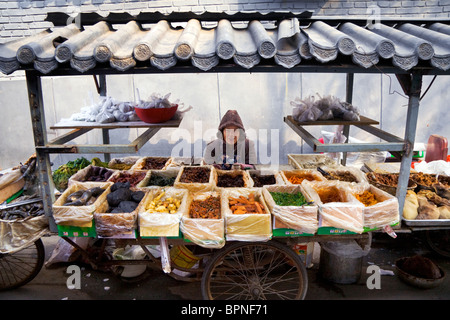 Eine glückliche Dame Angebote ihrem Marktstand Lebensmittel in den alten Gassen von Peking. Stockfoto