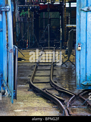 Einem Gleis führt in einem Industriegebäude mit blauen Türen Stockfoto