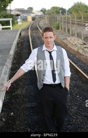 junge weiße männliche Zauberer mit Ingwer Haar posiert außerhalb auf stillgelegten Bahn verfolgt Stockfoto