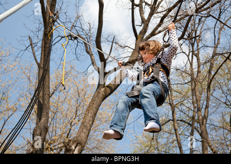 Kleines Mädchen mit einem Bungee-Seil im Park im Frühjahr Prellen. Stockfoto