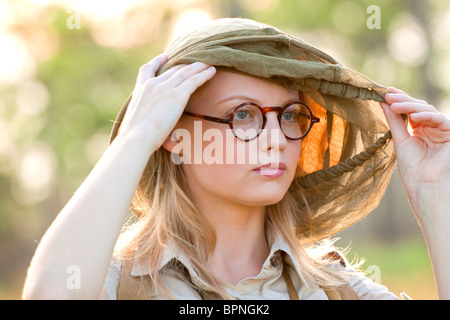 Junge Frau in Brillen tragen eine Moskitonetz-Kapuze Stockfoto