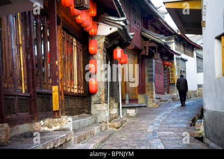 Ein chinesischer Mann geht auf einer gepflasterten Straße in die historische Stadt von Lijiang, UNESCO-Weltkulturerbe, Provinz Yunnan, China Stockfoto