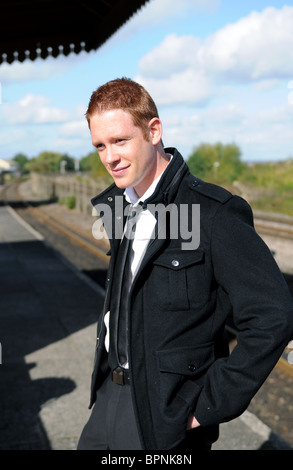 junger weißer Mann mit Ingwer Haar posiert auf einem stillgelegten Bahnhof außerhalb Stockfoto