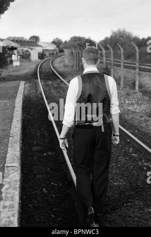 junge weiße männliche Zauberer mit Ingwer Haar außerhalb zu Fuß auf stillgelegten Bahngleisen Stockfoto
