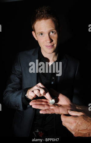 junge weiße männliche Magier im schwarzen studio Stockfoto