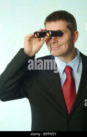 Lächelnder Mann in einem Anzug, der Blick durch ein Fernglas Stockfoto