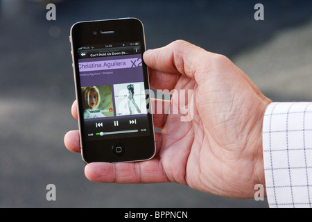 Das iPhone 4 in der Handfläche einer Hand eines Mannes, Spotify mit Christina Aguilera zeigen. Stockfoto