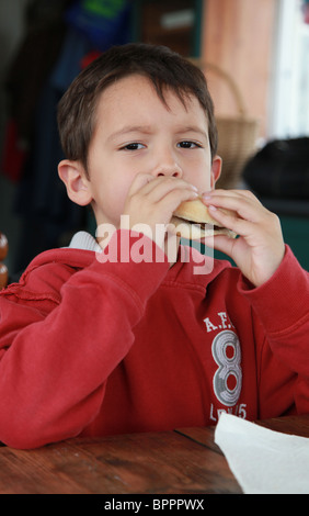 Kleiner Junge einen Hamburger Essen. Stockfoto