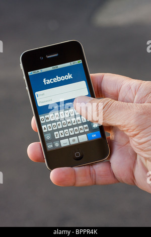 Das iPhone 4 in der Handfläche der Hand eines Mannes. Auf dem Bildschirm sehen Sie die Facebook-app. Stockfoto