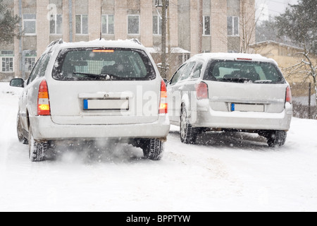 Zwei silberne europäische Autos auf verschneiten Straßen. Stockfoto