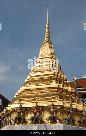 Dämonen bewachen unten eine vergoldete Chedi, in den Tempel des Smaragd-Buddha (Wat Phra Kaeo), Grand Palace, Bangkok, Thailand Stockfoto