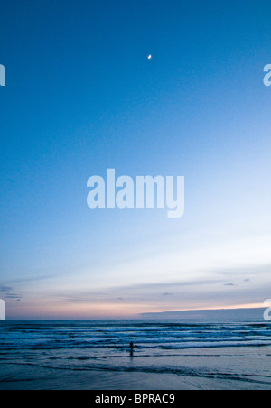 Eine Surfer verlässt den Pazifischen Ozean bei Sonnenuntergang. Stockfoto