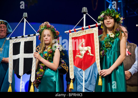 Junge Mädchen tragen Girlanden der Blumen hält Celtic Banner auf der Bühne während der Zeremonie bei National Eisteddfod of Wales 2010 Stockfoto