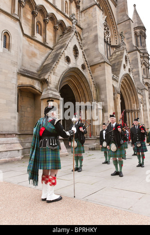 Mitglieder des Harpenden Pipe Band stehen außerhalb St Albans Abbey Stockfoto