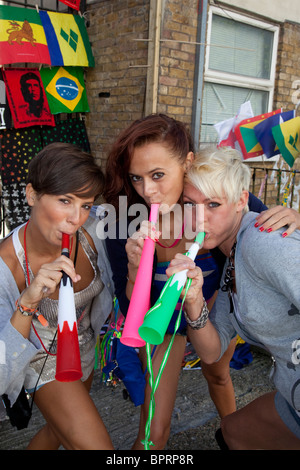 Notting Hill Carnival, drei freche Mädchen bläst Vuvuzelas, London, England, Vereinigtes Königreich Stockfoto