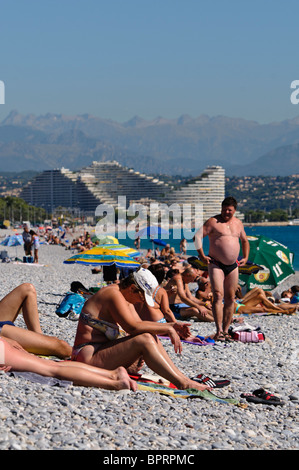 Menschenmassen am Kiesstrand in Antibes und Villeneuve Loubet, mit Blick auf Nizza. Stockfoto