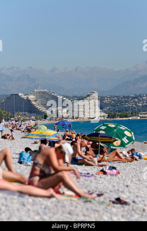 Menschenmassen am Kiesstrand in Antibes und Villeneuve Loubet, mit Blick auf Nizza. Stockfoto