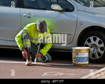 Des Rates Arbeiter malen weiße Linie auf Parkplatz Bucht - Frankreich. Stockfoto