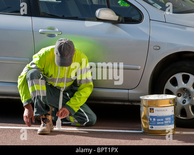 Des Rates Arbeiter malen weiße Linie auf Parkplatz Bucht - Frankreich. Stockfoto