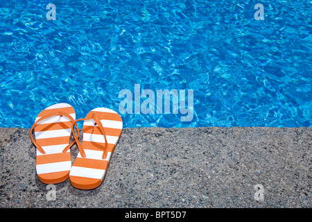 Hübsches Paar stripey flip Flops oder Riemen neben einem glitzernden blauen Swimming pool Stockfoto