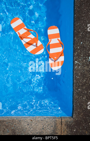 Hübsches Paar stripey Flip-Flops oder Riemen in einen glitzernden blauen Swimmingpool Stockfoto