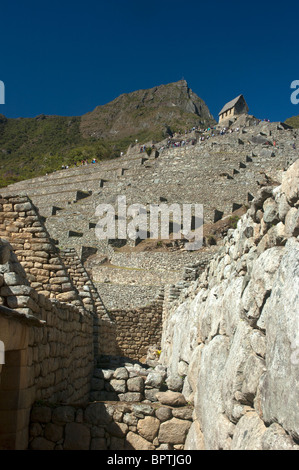 Touristen in das komplizierte Mauerwerk der zerstörten Gebäude an der alten Inka-Stadt Machu Picchu, Peru. Stockfoto