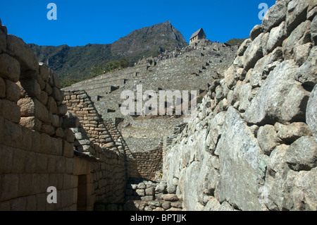 Touristen in das komplizierte Mauerwerk der zerstörten Gebäude an der alten Inka-Stadt Machu Picchu, Peru. Stockfoto