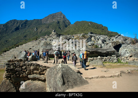 Touristen in das komplizierte Mauerwerk der zerstörten Gebäude an der alten Inka-Stadt Machu Picchu, Peru. Stockfoto