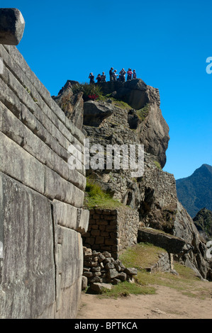 Touristen in das komplizierte Mauerwerk der zerstörten Gebäude an der alten Inka-Stadt Machu Picchu, Peru. Stockfoto