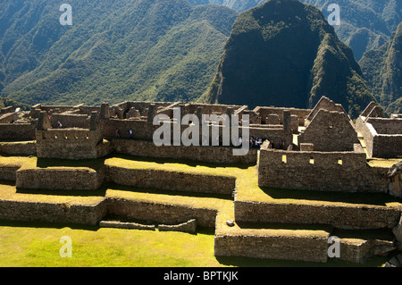 Touristen in das komplizierte Mauerwerk der zerstörten Gebäude an der alten Inka-Stadt Machu Picchu, Peru. Stockfoto