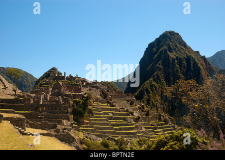 Touristen inmitten der komplizierten Steinarbeiten von zerstörten Gebäuden und Gartenterrassen an der alten Inka-Stadt Machu Picchu, Peru. Stockfoto