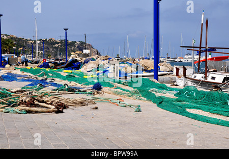 Blick auf den Fischerhafen (Port) entlang der Uferstraße in Puerto Andtatx mit bunten Fischnetz und ein Anker Stockfoto
